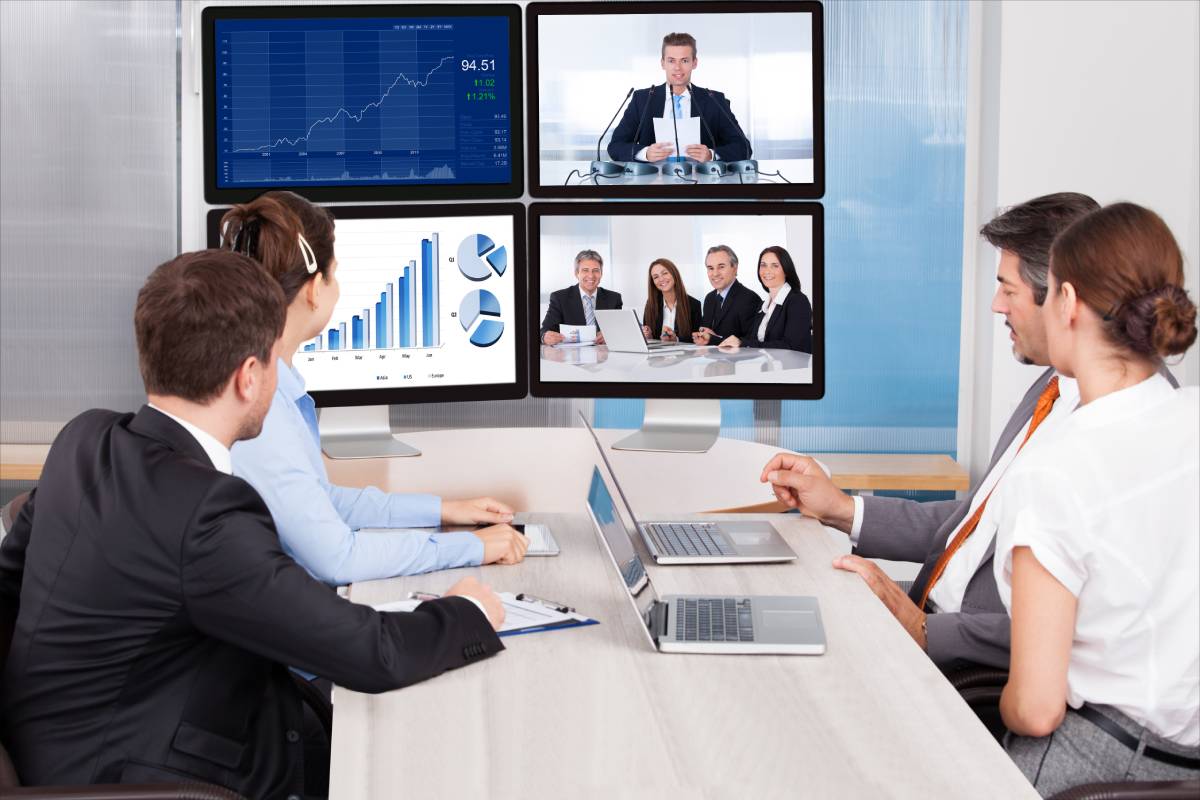 Four business people collaborating with coworkers via video conference